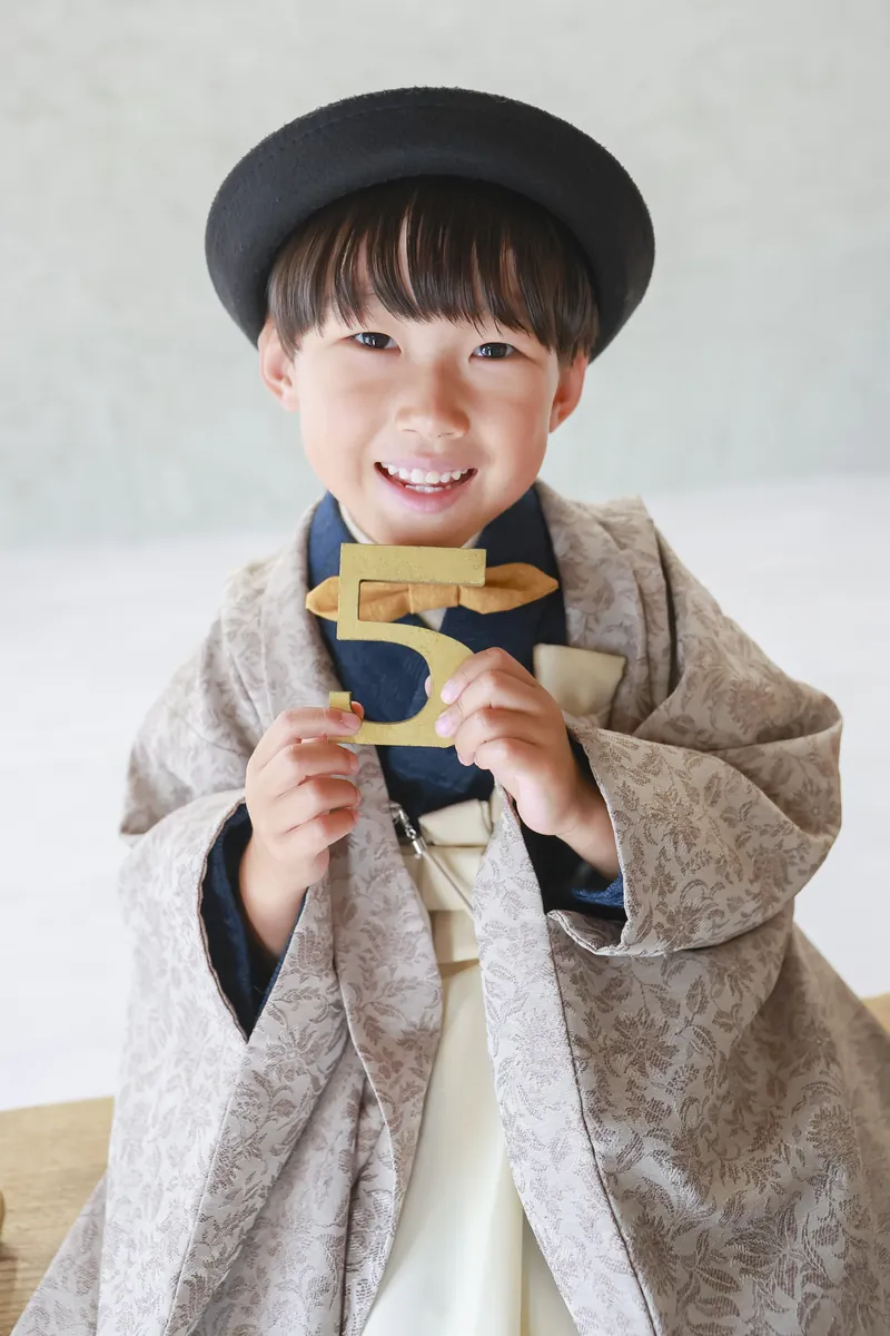 羽織袴を着て「5」の飾りを持つ5歳の七五三の男の子
