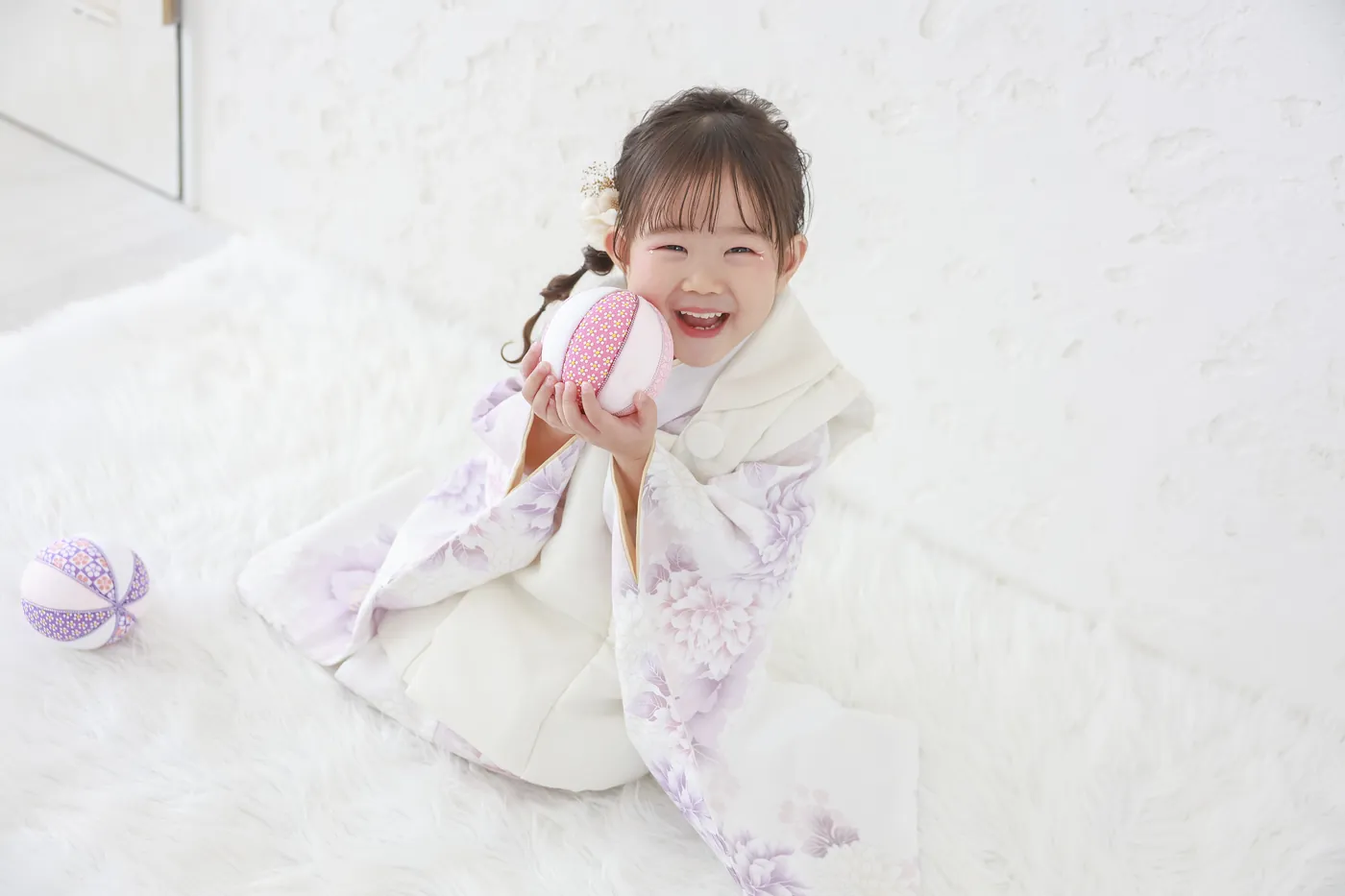 白いスタジオで被布を着て笑う3歳の女の子