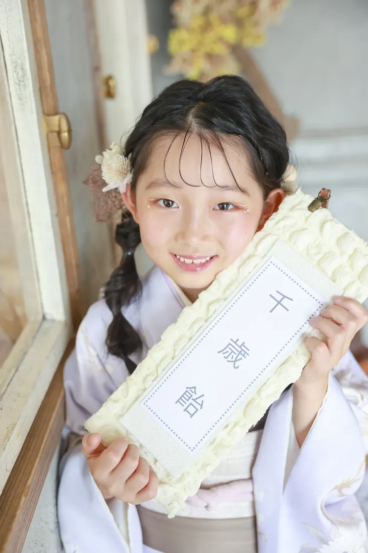 ヘアセットと髪飾りが映える、千歳飴を持つ七五三の女の子