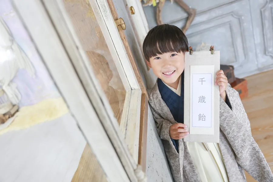 千歳飴を持ってのぞき込む七五三の男の子