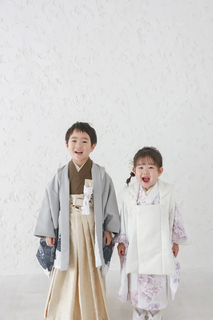 白い壁の前で笑う、七五三の兄妹